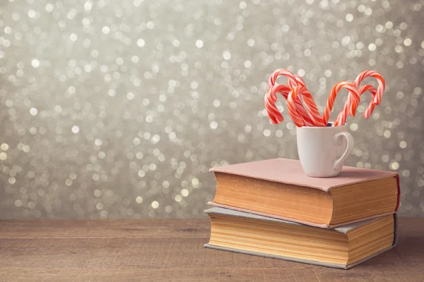 Bastones de caramelo y taza en los libros — Foto de Stock
