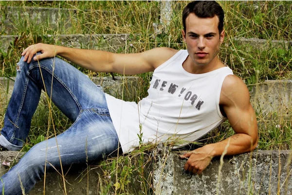 Fashionabla mannen i vit skjorta och jeans på bakgrund av naturen. — Stockfoto
