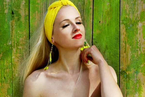 Hermosa chica rubia en una bufanda amarilla sobre un fondo verde  . — Foto de Stock