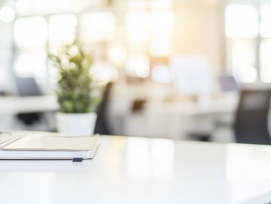 Çalışma alanı, arka planda bitki ve bulanık ofis alanlarının bulunduğu temiz bir masayı gösterir..