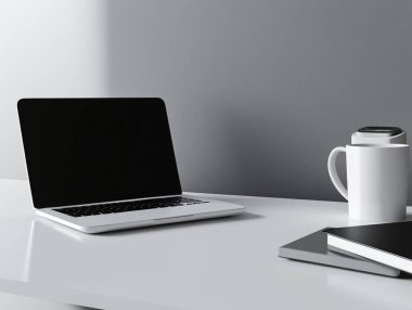 Masa düzeneği, modern bir ofiste dizüstü bilgisayar, defter ve kahve fincanı gösteriyor..