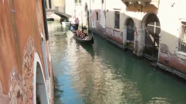 Venedik - 24 Temmuz 2018: Bir çift Venedik, İtalya 'daki Sessiz Kanal' da Bir Gondolda Yolculuğun Tadını Çıkarıyor. Sıcak ve güneşli bir günde antik Venedik binaları arasında seyahat etmek.