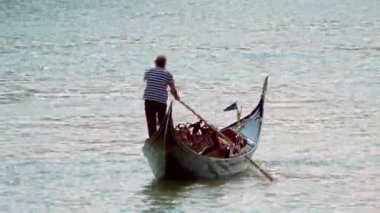 Venedik - 24 Temmuz 2018: Güneşli bir günde İtalya 'nın Venedik şehrinde Güzel Mavi Su' da Yalnız Gondolcu. Gondolcuyu ve Gondolcuyu izole etmek çok zor..