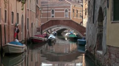 Venedik - 24 Temmuz 2018: Bir adam Venedik, İtalya 'daki teknesine ulaşmak için sessiz bir kanalı kaplayan bir duvar boyunca tırmanıyor..