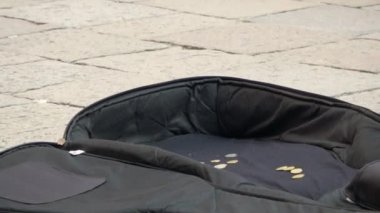 24 Temmuz 2018 'de gitar çalan ve para alan bir sokak sanatçısı. Gitar çantasının yakınından yavaşça uzaklaşırken genç bir dişi biraz para ekliyor. Çekimler geniş açıdan tamamlanıyor.