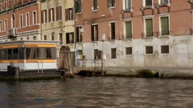 VENICE - 24 Temmuz 2018: Büyük Kanal, Venedik, İtalya 'da bir su otobüsü terminalini ve motorlu botları geçmek. Güneşli bir günde hareket halindeki bir teknenin önünden sabit bir atış..
