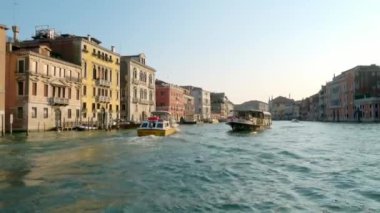 Venedik - 24 Temmuz 2018: Büyük Kanal, Venedik, İtalya 'da yaklaşan bir su otobüsünü geçiyoruz. Sıcak bir yaz gününde, akşamın altın ışığında hareket eden bir teknenin önünde sabit bir manzara..