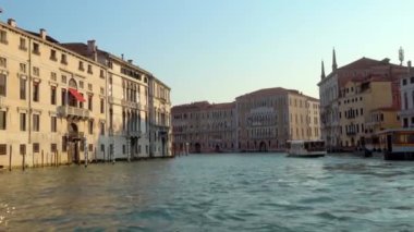 VENICE - 24 Temmuz 2018: Büyük Kanal boyunca uzanan bir su otobüsünü takip ederek Venedik, İtalya 'da güzel bir yaz akşamında tarihi binaların camlarında altın ışık parlarken.