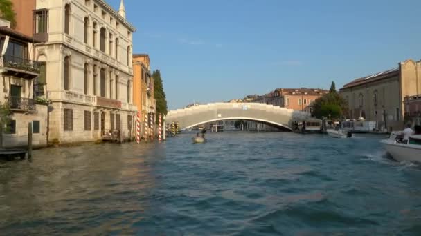 Venice 2018年7月24日 イタリア ヴェネツィアのグランド キャナルにあるポンテ アカデミア橋に接近中のモーターボート 夕方の美しい黄金の光の中で動くボートの前から安定したショットワイドショット — ストック動画