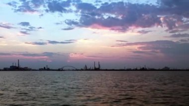 Gün batımında Venedik, İtalya yakınlarındaki bir köprüye ve endüstriyel komplekse yakınlaş. Hareket halindeki bir tekneden sabit atış..