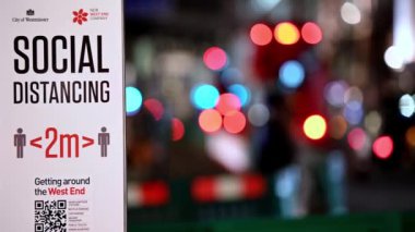 LONDON - 3 Kasım 2020: Arka planda odaklı trafik farları olmayan sosyal uzaklık uyarı işareti. Sığ alan bokeh etkisi