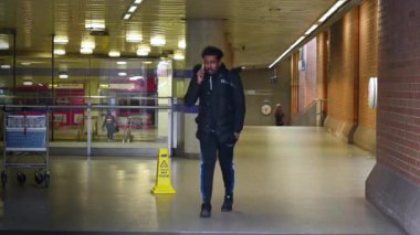 19 Mart 2020: Cep telefonu kullanan bir adam Coronavirus salgını sırasında neredeyse terk edilmiş King 's Cross St. Pancras metro bilet bölgesinden çıkıyor.