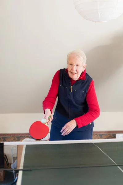 An elderly lady plays table tennis.