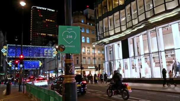 ロンドン 2020年11月3日 2Mの鮮やかな社会的距離標識で オックスフォードストリートクリスマスライトの下のトラフィックを背景に — ストック動画