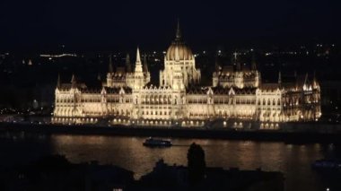 Gece Budapeşte, Macaristan 'daki Macar Parlamento Binası önünde Tuna Nehri' nden bir tekne geçiyor..