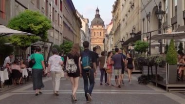 21 Ağustos 2018: Turistler, Macaristan 'ın başkenti Budapeşte' deki Aziz Stephen Bazilikası 'na doğru uzanan bir kafe boyunca yürüyorlar..