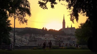Bir çift gün batımında Budapeşte, Macaristan 'daki Balıkçı Kalesi' nde el ele tutuşarak yürüyor..