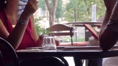 BÜDAPEST - 21 AĞUSTOS 2018: Ortağı cep telefonu kullanırken ve bir garson Budapeşte, Macaristan 'da bir açık hava kafede menülerini alırken serinlemek isteyen bir kadın