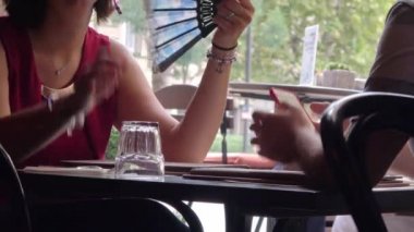 BUDAPEST - 21 Ağustos 2018: Ortağı Budapeşte, Macaristan 'da açık bir kafede otururken, bir kadının serinlemek için kendini yelpazelemesi