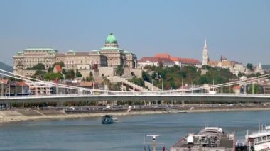 TELEPHOTO, arka planda Buda Kalesi ve Balıkçı Kalesi ile Elisabeth Köprüsü 'nün altından geçen bir teknenin fotoğrafını çekti. Macaristan, Budapeşte 'de güneşli bir gün.