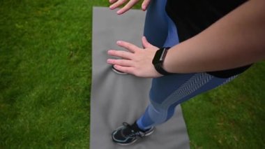 Yavaşça pov çekiminde kadın çimenlerin üzerindeki yoga minderinde ayak parmaklarına dokunmak için uzanır..