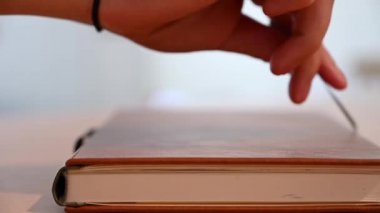 Deri kaplı bir kitabın, kitap şeridi işaretini çekerek açılışının, yavaş ve yüzeysel odak noktası görüntüsü.