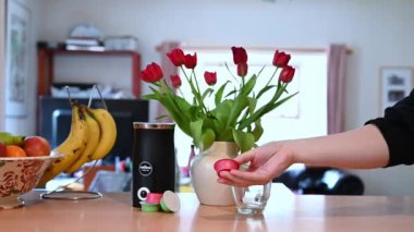 Richmond, Kuzey Yorkshire, İngiltere - 15 Mayıs 2020: Bir kahve makinesinin, meyve ve çiçeklerin yanında havaya fırlatılan ve tekrar yakalanan bir kahve kapsülünün sığ odaklı görüntüsü.