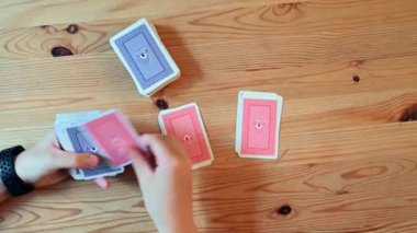 Kadın elinin tahta bir masanın üstünde bir deste iskambil kâğıdı dağıtırken çekilmiş fotoğrafı.