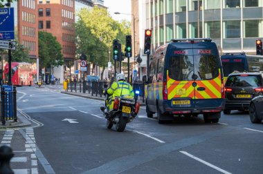 LONDON - 29 Mayıs 2021: İngiliz polis motosikleti kırmızı ışıkta polis minibüsünün yanından geçiyor
