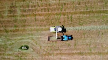 Havadan çekilen hava aracı, bir traktörü takip ederken, bir tahıl biçme makinesinin yanında, filizlenme için çim biçme makinası toplarken görüntülendi.