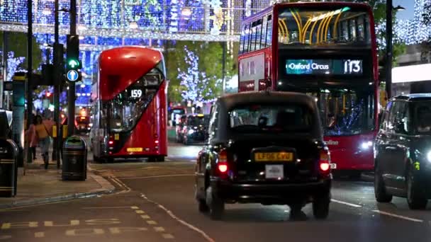 2020年11月3日 红色伦敦双层巴士和黑色伦敦出租车停在牛津街 背景是科维德19大流行期间的圣诞灯和购物者 — 图库视频影像