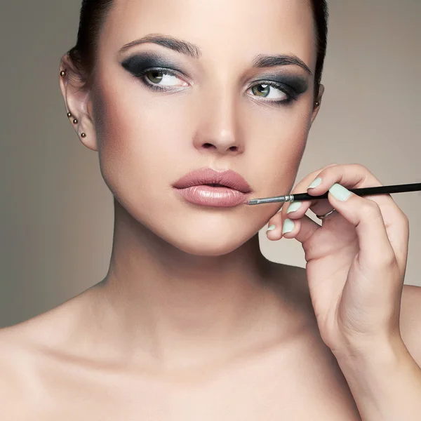 Schönes Frauengesicht. Beauty Girl mit Make-up.Make-up Artist trägt Lippenstift auf — Stockfoto