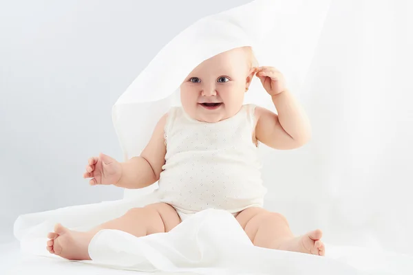 Smiling baby girl under the white blanket. little funny child — Stock Photo, Image