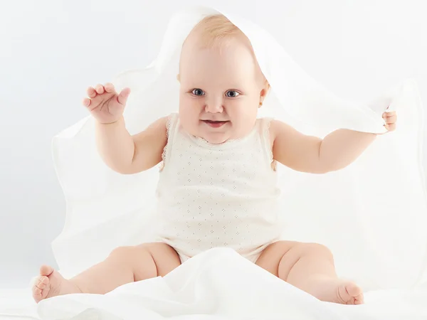 Leende flicka under vita täcket. lite rolig child.newborn — Stockfoto