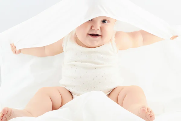 Leende flicka under vita täcket. lite rolig child.newborn — Stockfoto