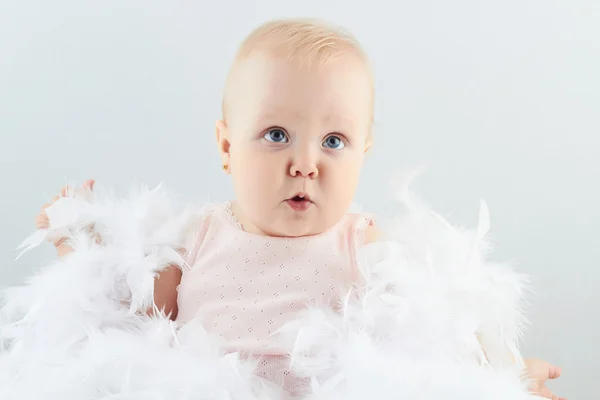 Leende flicka i fjädrar. lite rolig child.newborn — Stockfoto