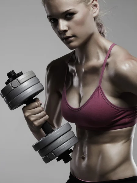 Athletic kvinna pumpa upp muskler med dumbbells.beautiful blond tjej i gym — Stockfoto