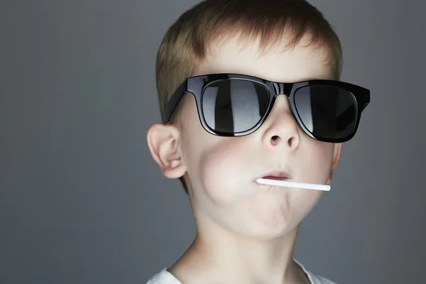 サングラスで面白い若い男の子を食べる A Lollipop.Fashionable 子 — ストック写真