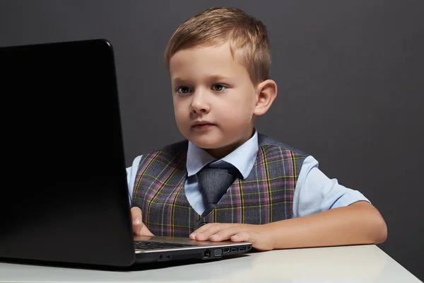 Мальчик смотрит в экран блокнота. смешной ребенок с компьютером — стоковое фото