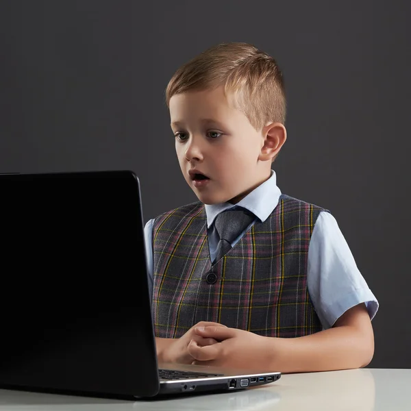 Мальчик смотрит в экран блокнота. смешной ребенок с компьютером — стоковое фото