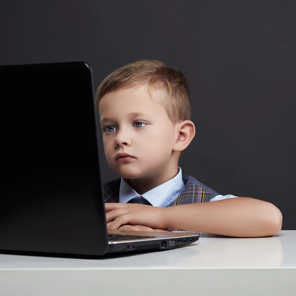 Мальчик с компьютером. Забавный ребенок смотрит в блокнот. образование — стоковое фото