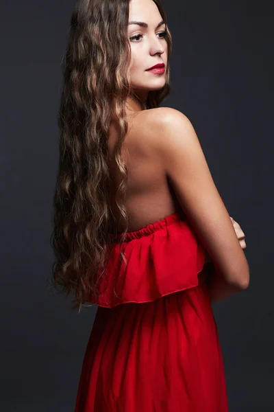 長い巻き毛と美しさの女性。赤いドレスで美しい少女 — ストック写真