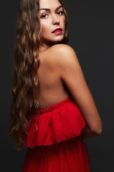 Piękna kobieta z długie kręcone włosy. Piękna dziewczyna w czerwonej sukience — Zdjęcie stockowe