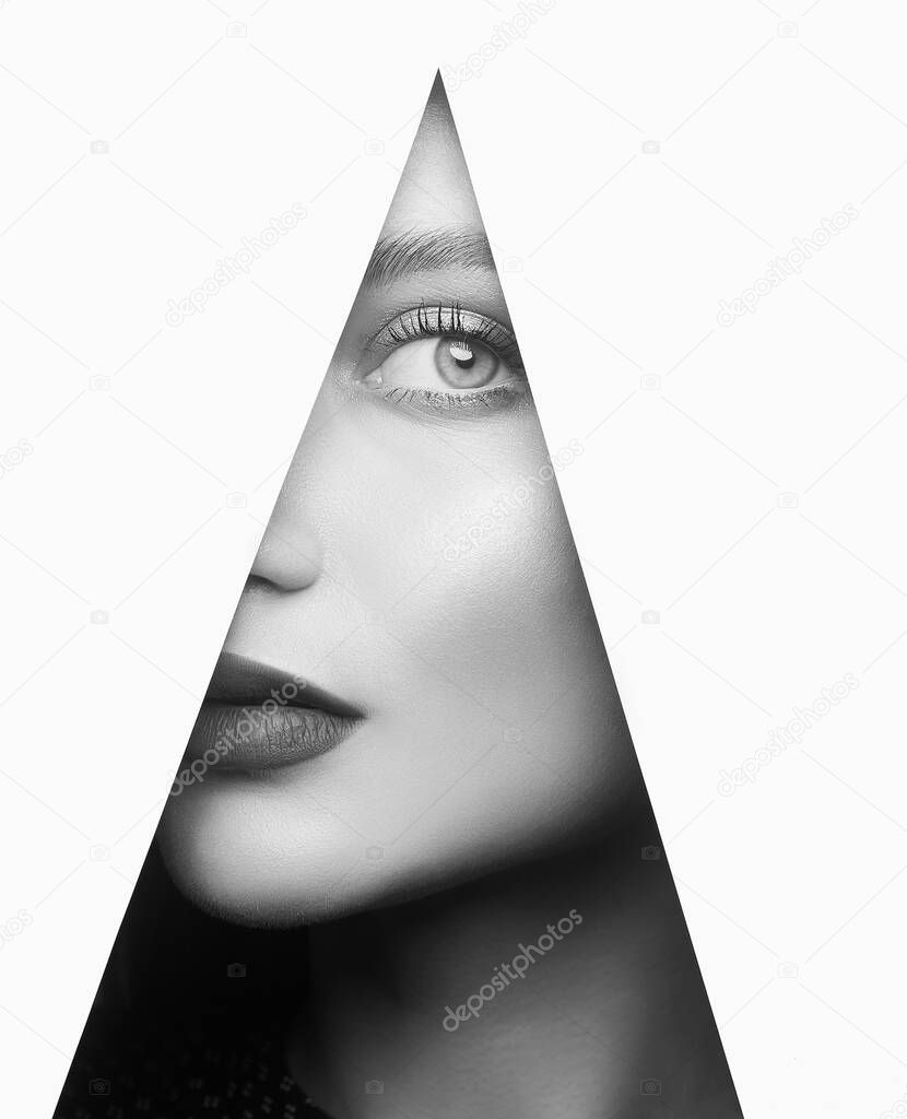 young beautiful woman in triangle. female face into paper hole, black and white portrait