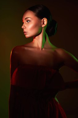 Renkli parlak ışıklar içinde güzel bir kadın. Kırmızı elbiseli kızın silueti.