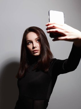 Güzel genç bir kadın akıllı telefondan selfie çekiyor. Güzel makyöz kız, bir film yap.
