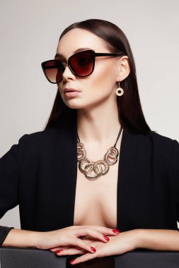 Güneş gözlüklü ve mücevherli güzel seksi bir kadının moda portresi. Altın elbiseli güzel kız