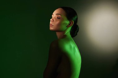 Renkli ışıklar içinde güzel bir genç kadın. Makyajlı ve parlak vücutlu güzel kız.