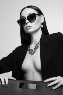 Güneş gözlüğü ve mücevher takmış güzel, siyah beyaz bir kadın portresi. Siyah gözlüklü güzel kız.