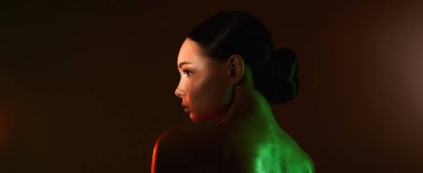 Renkli ışıklar içinde güzel bir genç kadın. Makyajlı ve parlak vücutlu güzel kız.